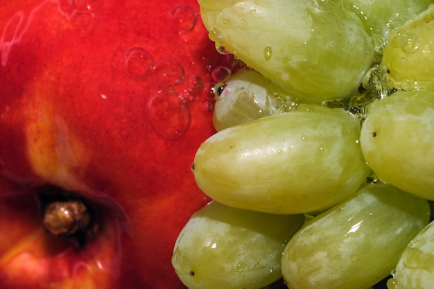 Raisins blancs sans pépins en grappe et nectarine sous un jet d'eau propre macrophotographie en gros plan