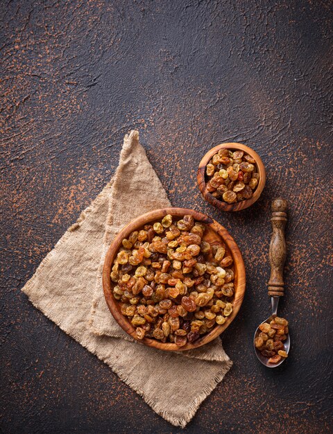 Raisins dans un bol en bois sur fond rouillé