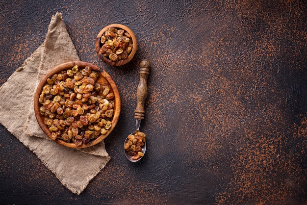 Raisins dans un bol en bois sur fond rouillé