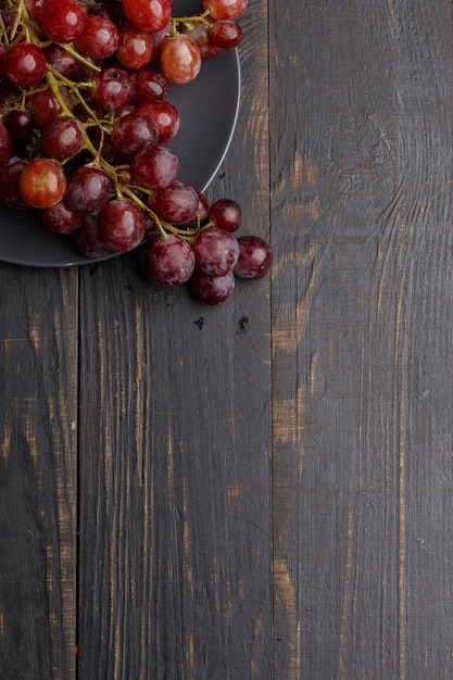 Raisins juteux mûrs sur une plaque sur un bois sombre. Vue de dessus.