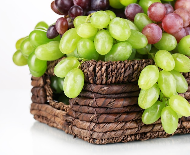 Raisins mûrs verts et violets dans le panier isolé sur blanc