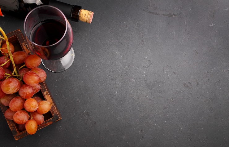 Photo raisins mûrs, vin rouge et un verre sur un fond noir