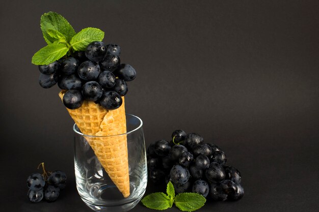 Raisins noirs dans le cornet de crème glacée sur fond sombre. Espace de copie. Fermer.