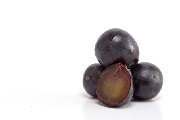 Raisins noirs frais sur blanc