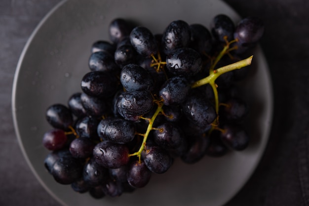 Raisins noirs juteux dans une plaque grise