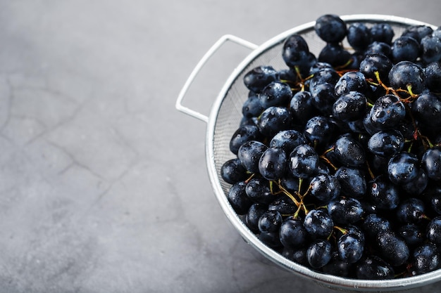 Raisins noirs mûrs dans un bol en métal sur fond noir. Vue de dessus