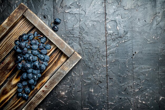 Raisins noirs sur un plateau en bois