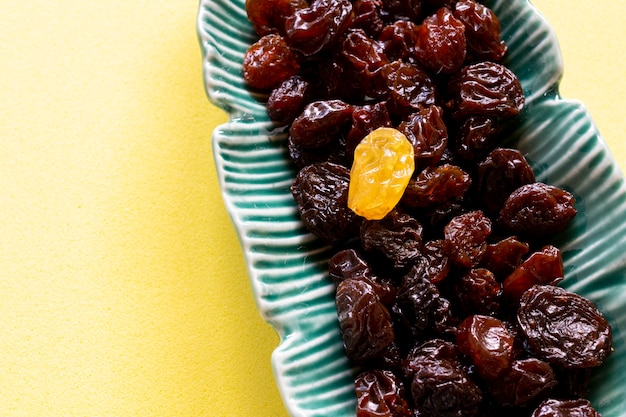 Photo raisins noirs avec un raisin léger dans le pot en céramique verte.