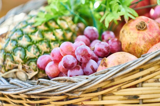 Photo des raisins, des pommes et des ananas sur un panier en osier brun