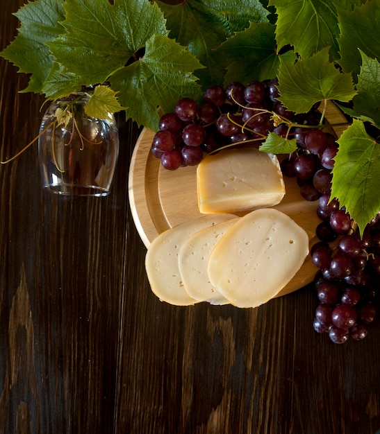 Raisins rouges avec des feuilles, verre de vin et fromage frais. Vue de dessus, gros plan.