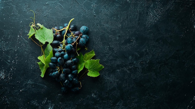 Raisins rouges frais avec des feuilles sur une table en pierre noire. Vue de dessus. Espace libre pour votre texte.