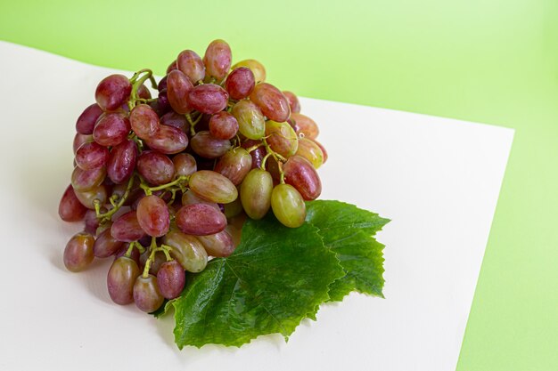 Photo raisins rouges et verts sur une feuille verte