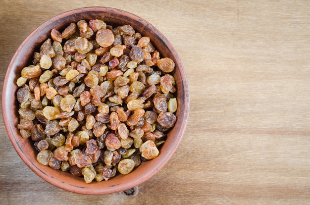 Raisins secs biologiques dans un bol sur fond en bois.