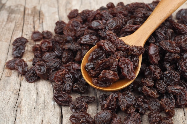 Raisins secs biologiques dans une cuillère en bois sur fond de table en bois ancien