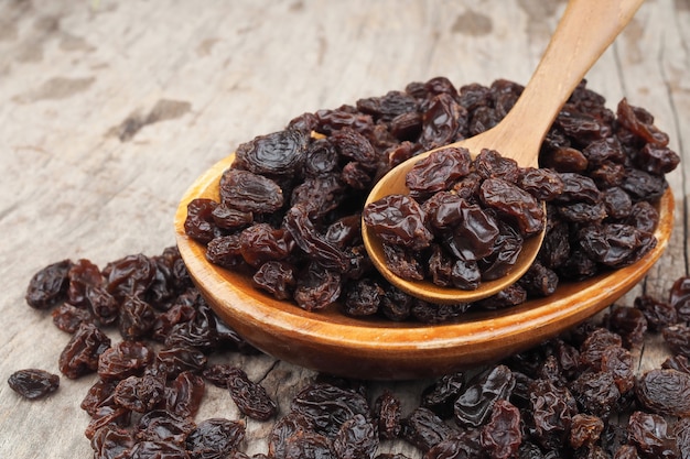 Raisins secs biologiques dans la cuillère de bois sur la table en bois