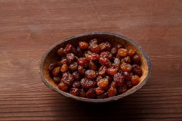 Raisins secs dans un bol de noix de coco sur une table en bois