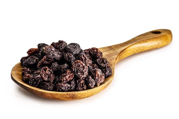 Raisins secs séchés fabriqués au Brésil dans une cuillère en bois rustique isolé sur fond blanc