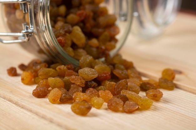 Photo les raisins secs sont versés d'un bocal en verre sur la table.