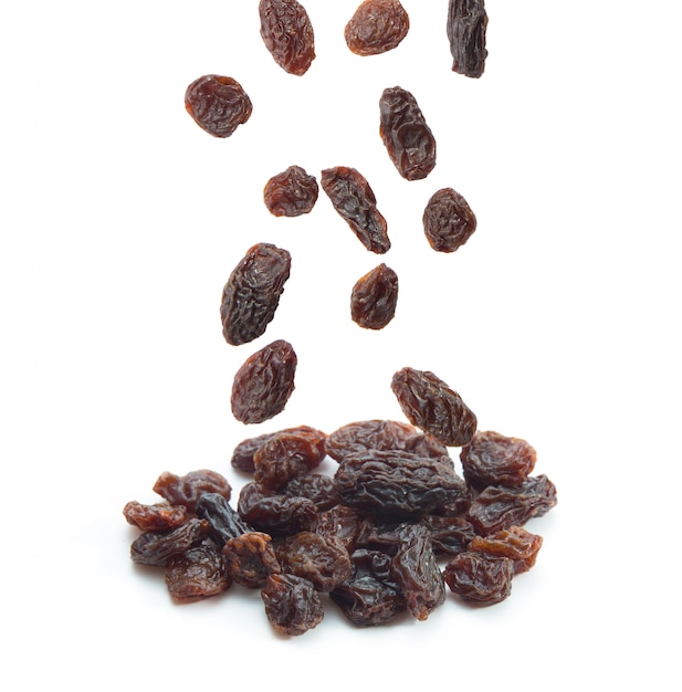 Raisins secs tombant isolé sur fond blanc