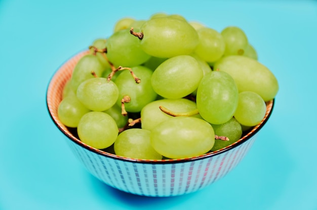 Raisins de table verts sur bol sur fond bleu. Régime équilibré