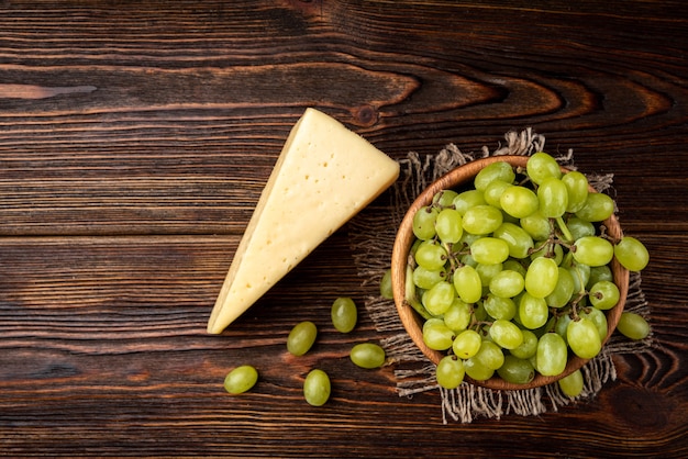 Raisins verts avec du fromage sur un bol en bois sur la table