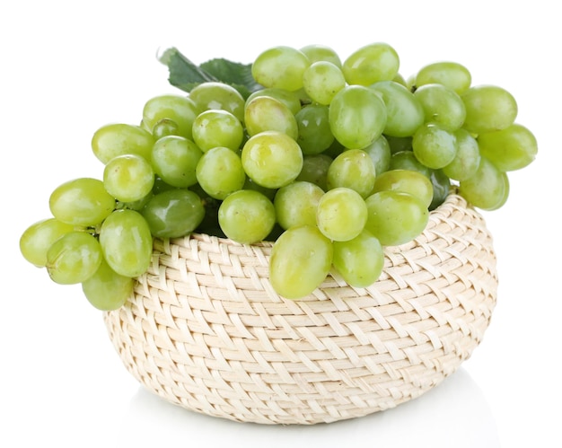 Raisins verts mûrs dans le panier isolé sur blanc