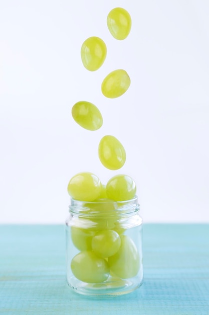 Raisins verts tombant dans un bocal en verre