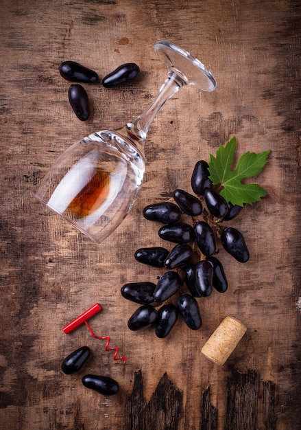 Raisins, vin rouge, verre, tire-bouchon et liège vue de dessus