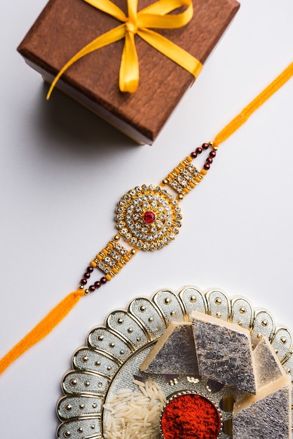 raksha bandhan saluant rakhi et cadeau avec du kaju katli sucré ou du mithai et des grains de riz kumkum