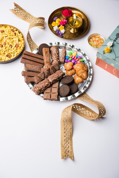 Raksha bandhan Salutations du festival : Rakhi conceptuel fait à l'aide d'une assiette pleine de chocolats et de biscuits avec bande fantaisie et pooja Thali. mise au point sélective