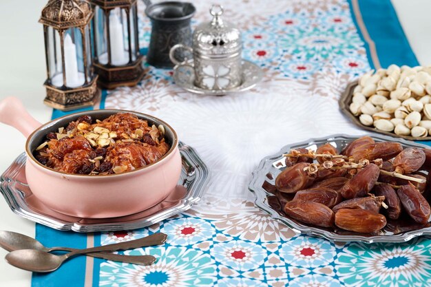Ramadan Kareem et iftar concept de vacances alimentaires musulmanes Umm Ali Dayes Fruits et pistaches avec thé et lanternes avec bougies Idée de célébration