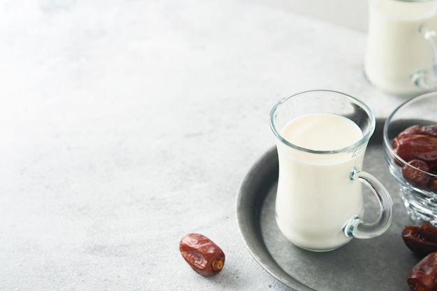 Ramadan Kareem nourriture et boissons Assiette de dattes verre de lait et branche de palmier dattier sur fond gris clair Mode de vie musulman juste Place pour le texte Mise au point sélective