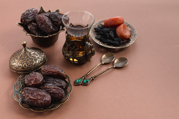 Photo ramadan karim avec verre à thé; dates premium et fruits secs arabes sur fond marron