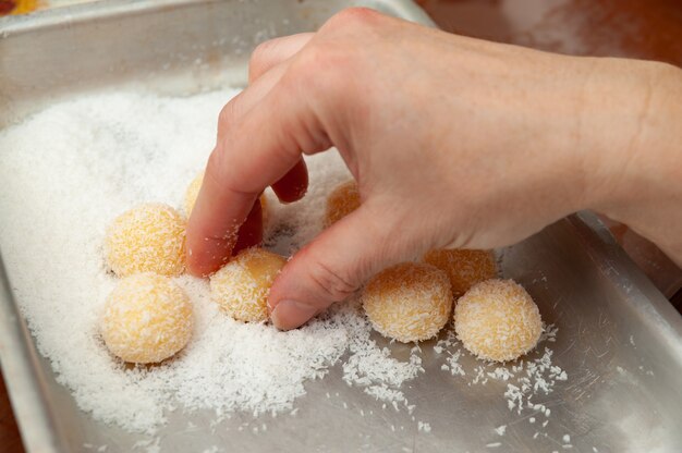 Ramasser à la main un bonbon traditionnel brésilien appelé Beijinho de Coco en portugais brésilien