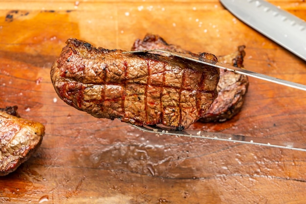 ramasser le steak de boeuf de picanha avec des pinces métalliques