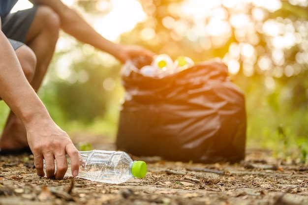 Ramassez les bouteilles en plastique dans le jardin. Environnementalisme et sensibilisation au plastique. Nettoyage des forêts.