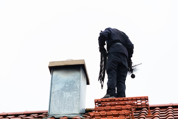 Photo ramoneur sur le toit de la maison de travail