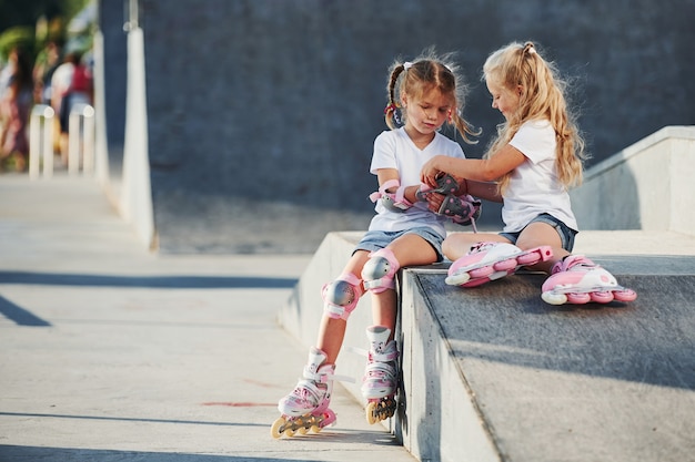 Sur la rampe pour les sports extrêmes. Deux petites filles avec des patins à roulettes à l'extérieur s'amusent.