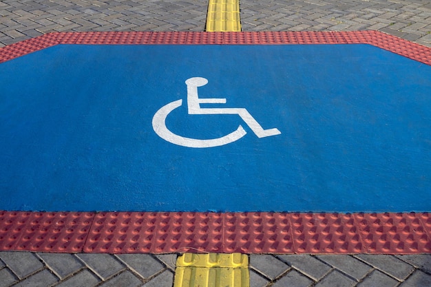 Rampe avec signe pour l'accès en fauteuil roulant sur le trottoir. Revêtement de sol tactile pour les malvoyants.