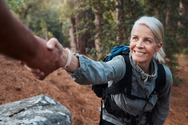 Randonnée coup de main et personnes dans la nature pour l'aventure d'escalade bien-être des seniors et soutien à la santé Femme heureuse ou couple d'amis mains atteignant le travail d'équipe sur les montagnes ou le trekking en forêt
