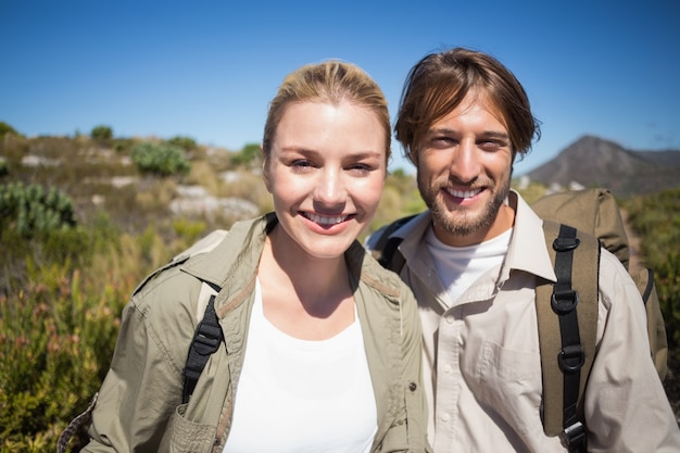 Randonnée couple marchant sur le terrain de montagne, souriant à la caméra