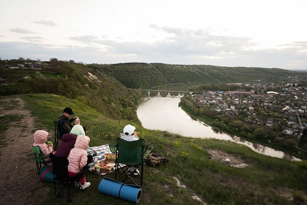 Randonnée en famille en vacances ayant un pique-nique en soirée au sommet de la montagne en regardant le magnifique paysage du canyon