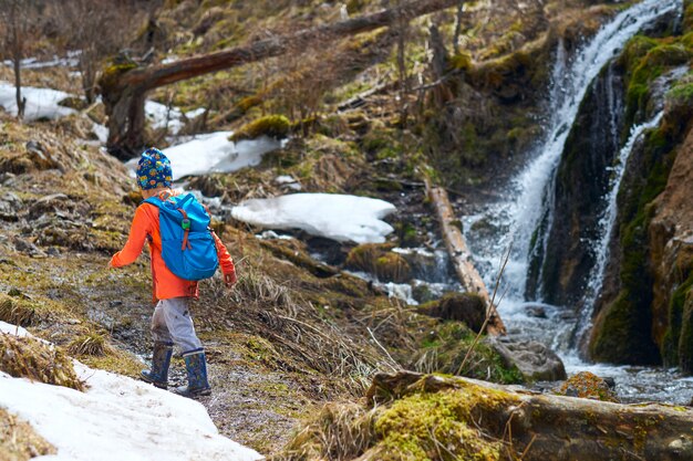 Randonnée petit enfant avec sac à dos en randonnée va près de la cascade