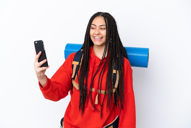 Randonneur adolescente avec des tresses sur fond blanc isolé faisant un selfie