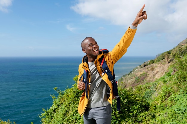 Photo randonneur afro-américain avec sac à dos pointant le doigt à l'extérieur