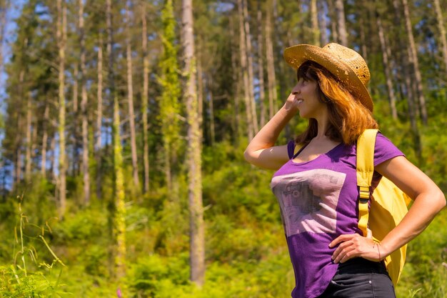 Un randonneur aventureux souriant à côté de quelques pins dans la forêt