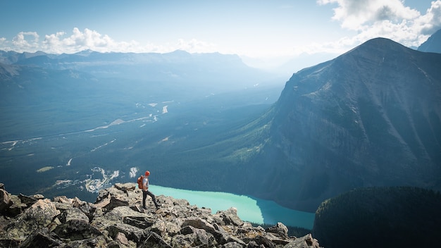 Randonneur bénéficiant d'une vue sur la vallée glaciaire et le lac après avoir atteint le sommet de la montagne