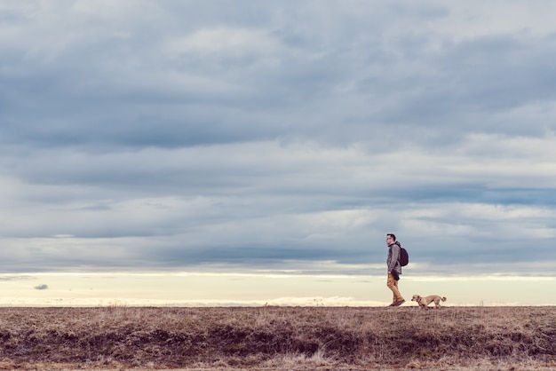 Randonneur et chien marchant dans les prairies