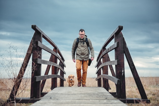 Randonneur et chien sur un pont en bois