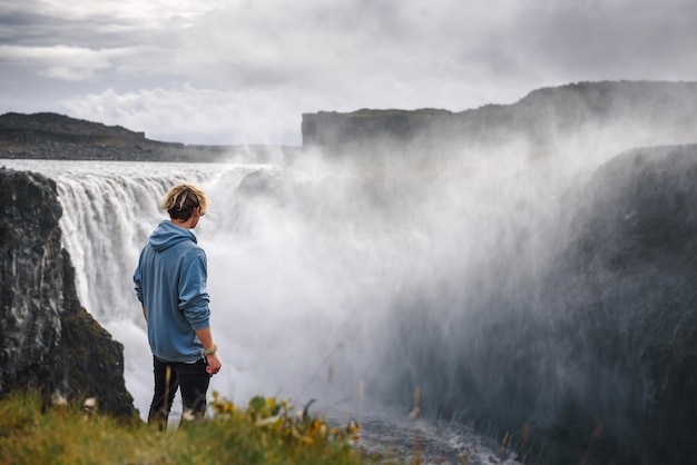 Randonneur debout au bord de la cascade dettifoss en islande